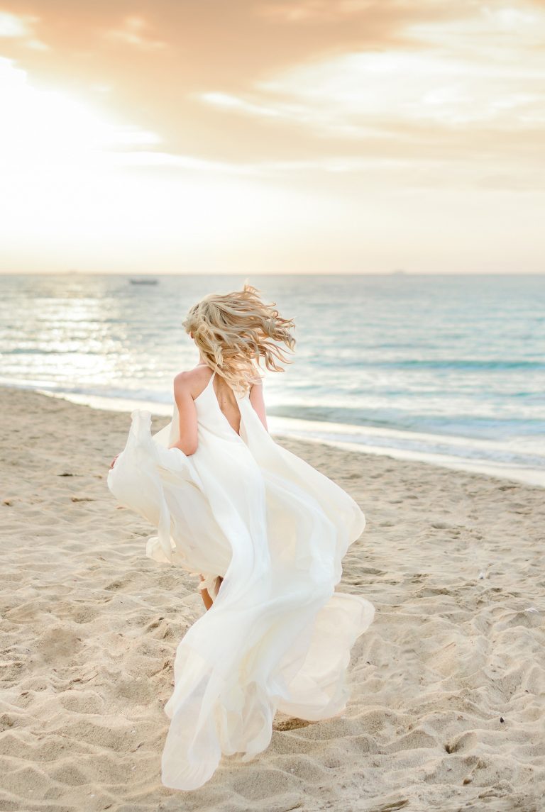 Beautiful stylish girl posing in sunlight on the beach